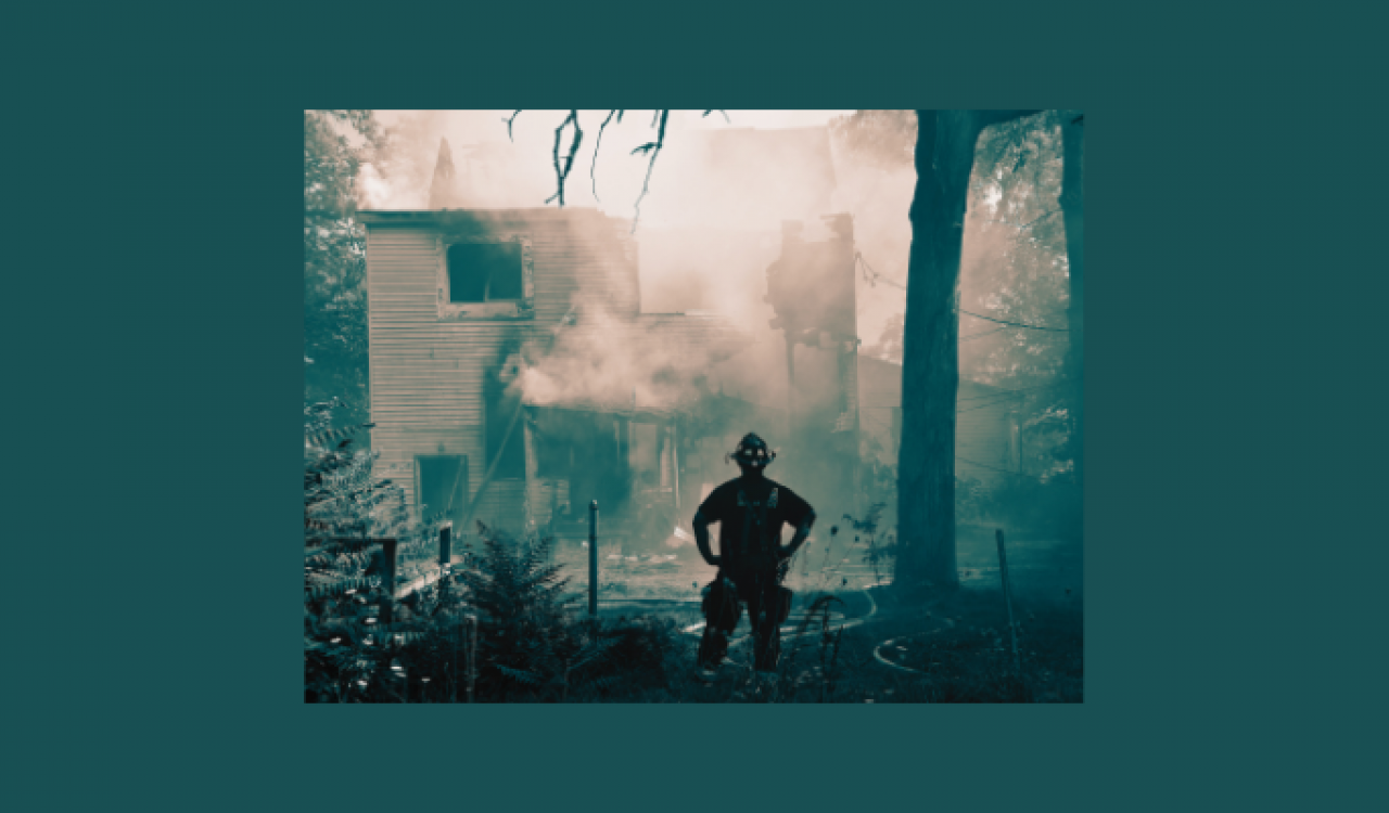 Firefighter looking at burned house